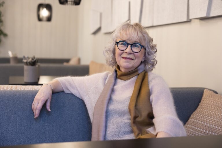 Hymyilevä kiharatukkainen silmälasipäinen nainen